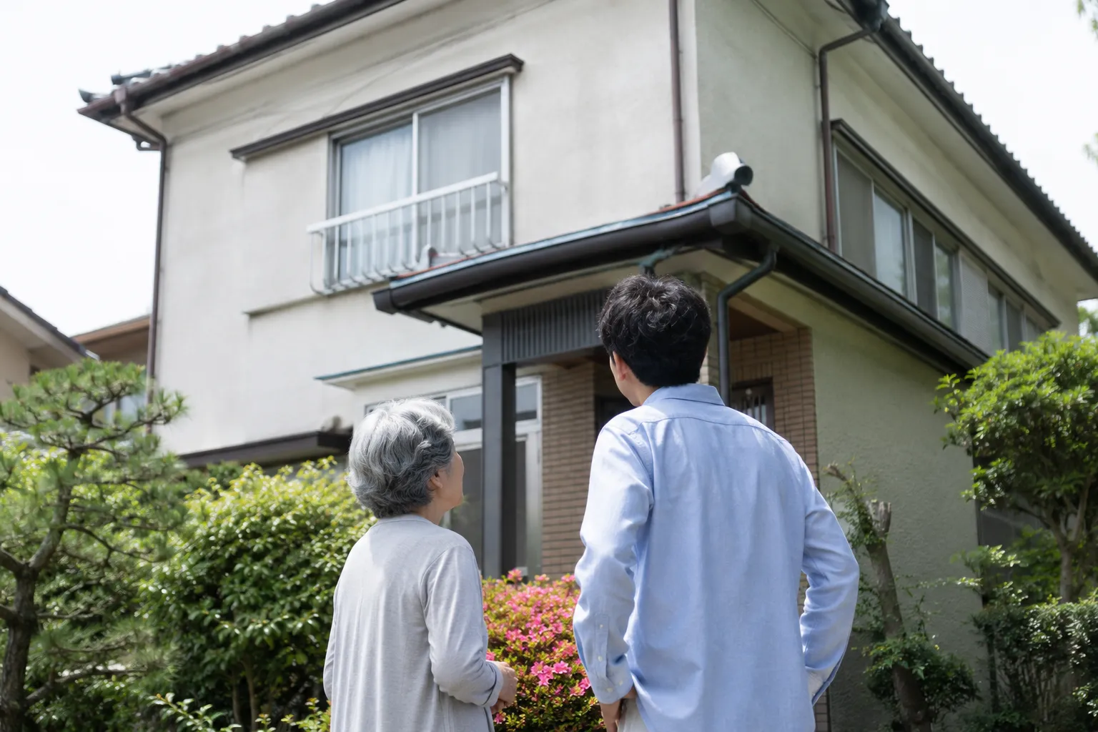 お盆に帰省した家族が実家の外壁や屋根の状態を親御さんと一緒に確認している様子